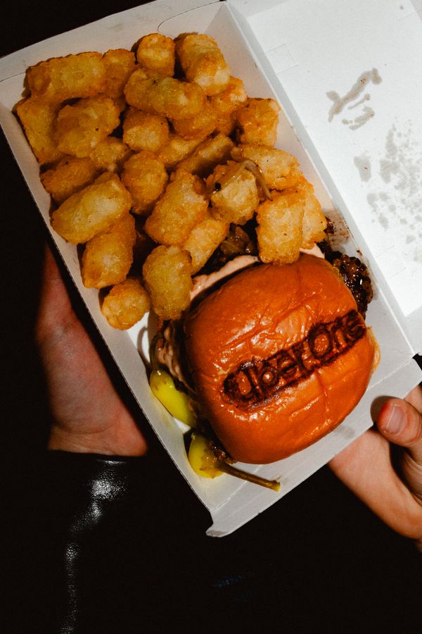 Tater tots and a smash burger with an Uber One branded bun, boxed at the event
